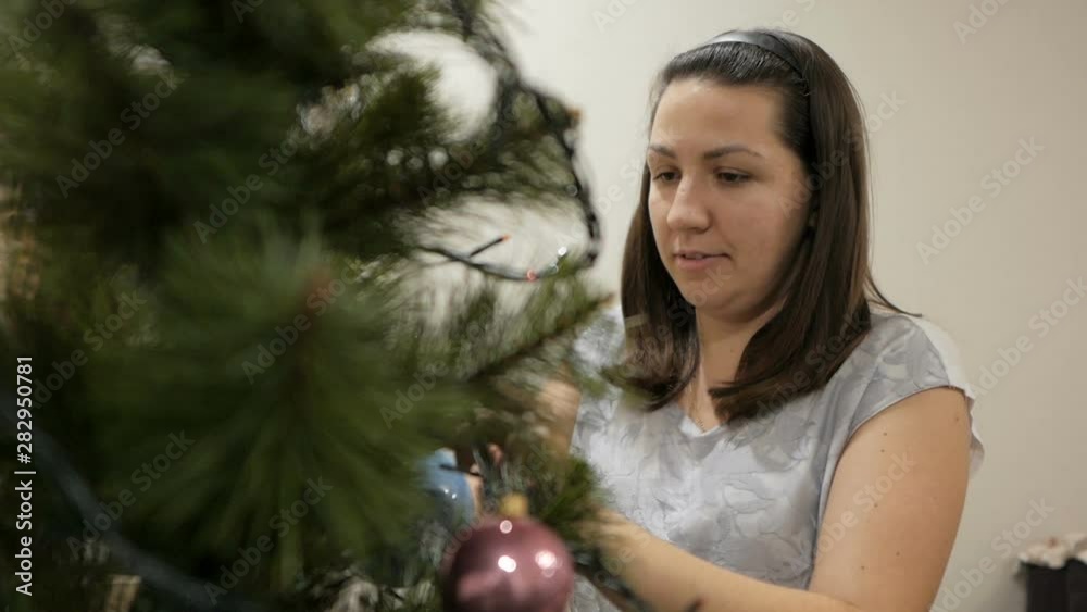 Happy family decorating a Christmas tree with boubles in the living-room Happy family decorating a Christmas tree with boubles in the living-room
