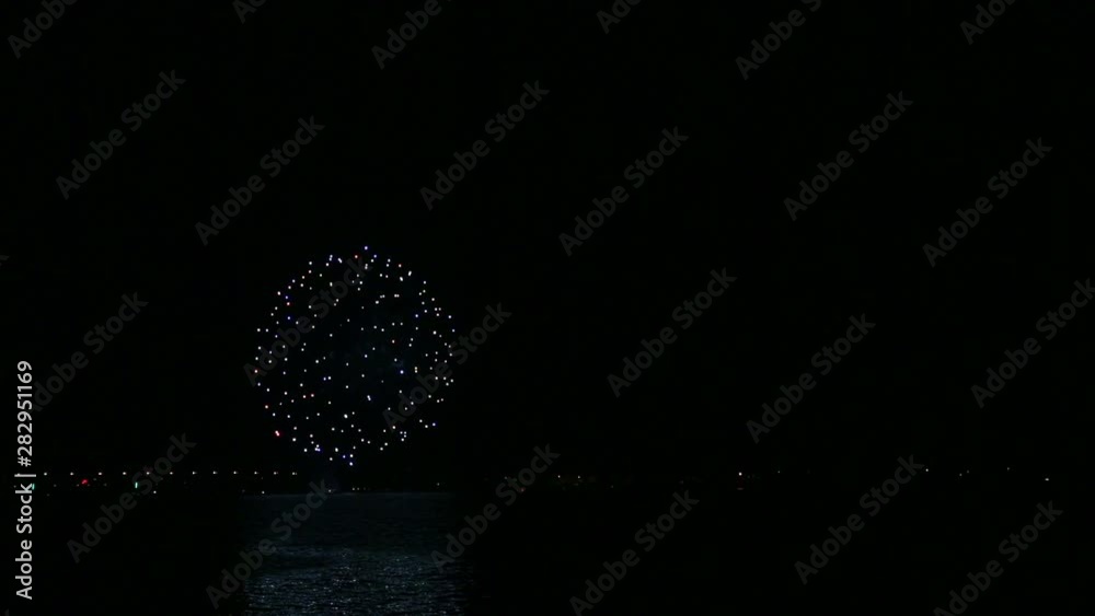 Sparkling festive fireworks in the night sky above the river reflecting in the water. Time laps Sparkling festive fireworks in the night sky above the river reflecting in the water. Time laps