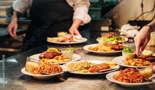 Food orders on the kitchen table in the restaurant, pasta spaghetti with tomato sauce and cheese, schnitzel with spaetzle