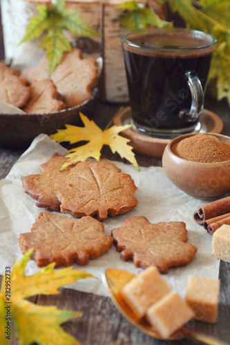 Autumn coffee break: cinnamon cookies in form of maple leaves, cup of coffee and yellow leaves