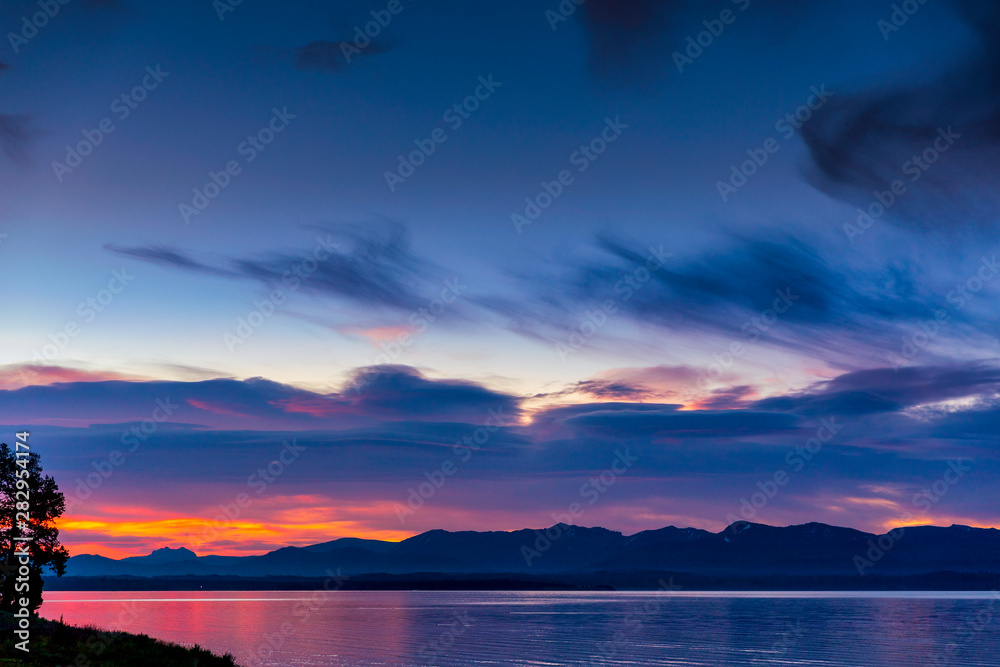Fototapeta premium Sunrise Above the Lake with Silhouetted Mountains