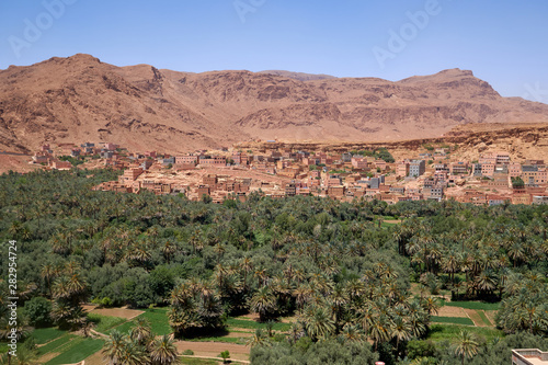 Panoramic view of the landscape with an ancient town Tinghir, a beautiful lush Green Oasis and palm grove surrounded by rocky Atlas Mountains at Todra Gorge in Morocco. 