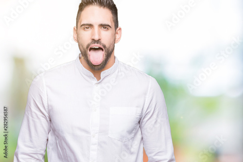 Young business man over isolated background sticking tongue out happy with funny expression. Emotion concept.