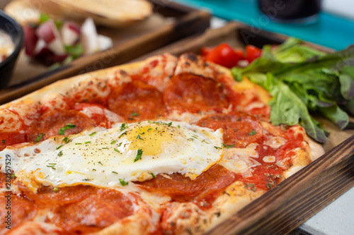 Close up of mouthwatering rome pizza with crust, tomato sauce, spicy pepperoni and fried egg in the centre