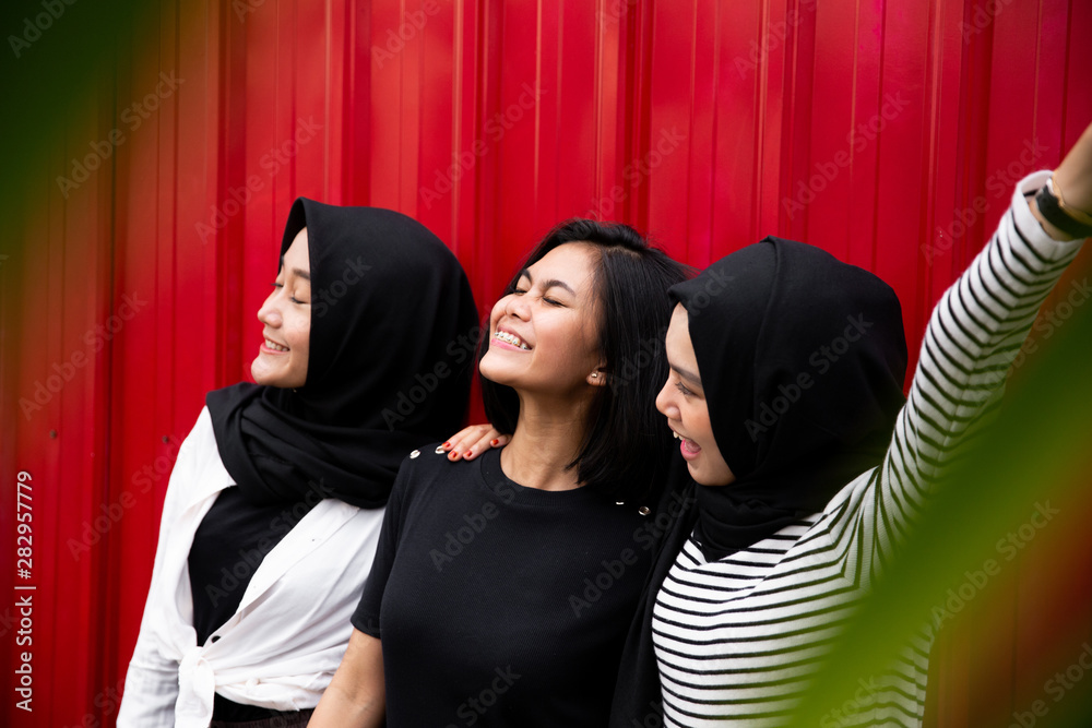 three women standing pose in front of the red background