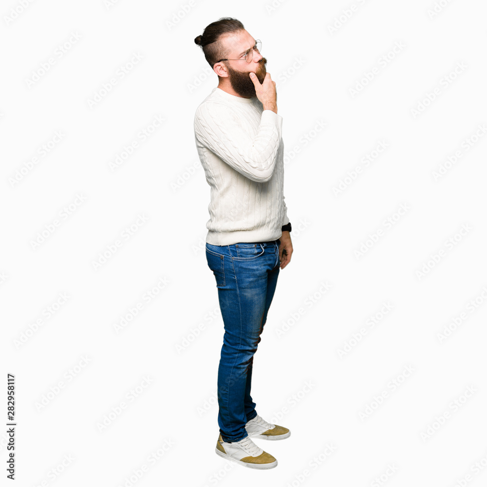 Young hipster man wearing glasses and winter sweater with hand on chin thinking about question, pensive expression. Smiling with thoughtful face. Doubt concept. Young hipster man wearing glasses and winter sweater with hand on chin thinking about question, pensive expression. Smiling with thoughtful face. Doubt concept.
