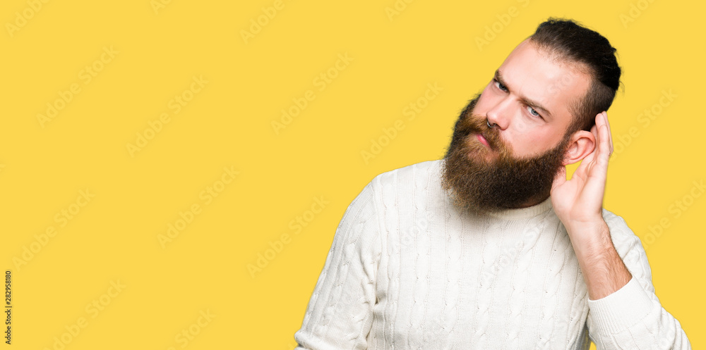 Young hipster man wearing winter sweater smiling with hand over ear listening an hearing to rumor or gossip. Deafness concept. Young hipster man wearing winter sweater smiling with hand over ear listening an hearing to rumor or gossip. Deafness concept.
