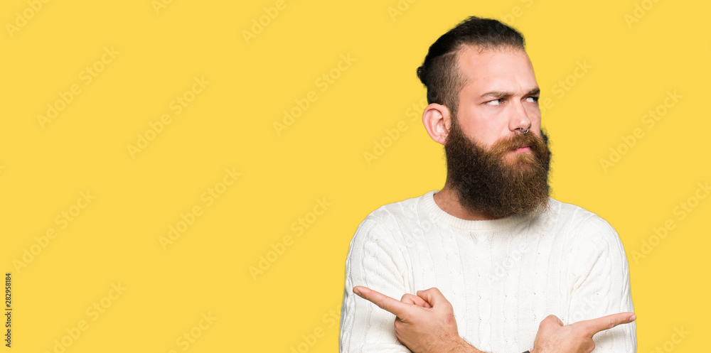 Young hipster man wearing winter sweater Pointing to both sides with fingers, different direction disagree Young hipster man wearing winter sweater Pointing to both sides with fingers, different direction disagree