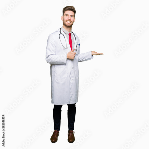 Young handsome doctor man wearing medical coat Showing palm hand and doing ok gesture with thumbs up, smiling happy and cheerful