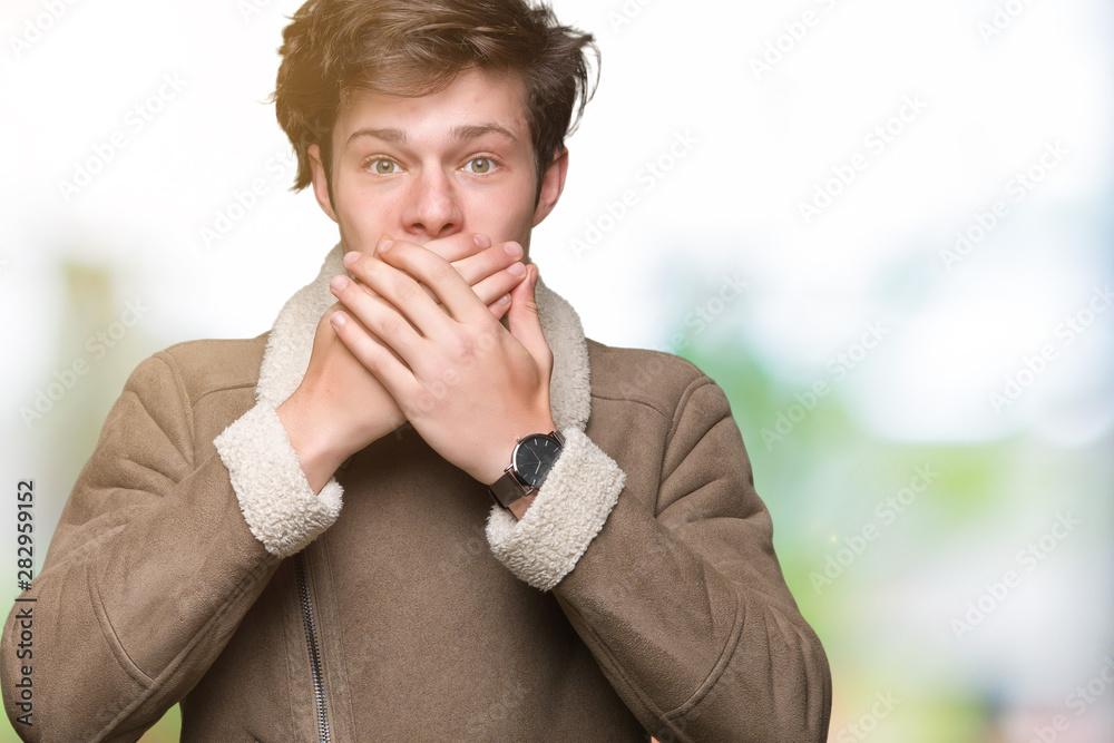 Young handsome man wearing winter coat over isolated background shocked covering mouth with hands for mistake. Secret concept. Young handsome man wearing winter coat over isolated background shocked covering mouth with hands for mistake. Secret concept.