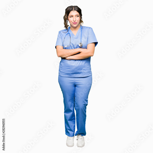 Young adult doctor woman wearing medical uniform smiling looking side and staring away thinking.