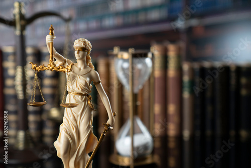 The law concept background. White statue of Themis and legal books on the table in the old court library.