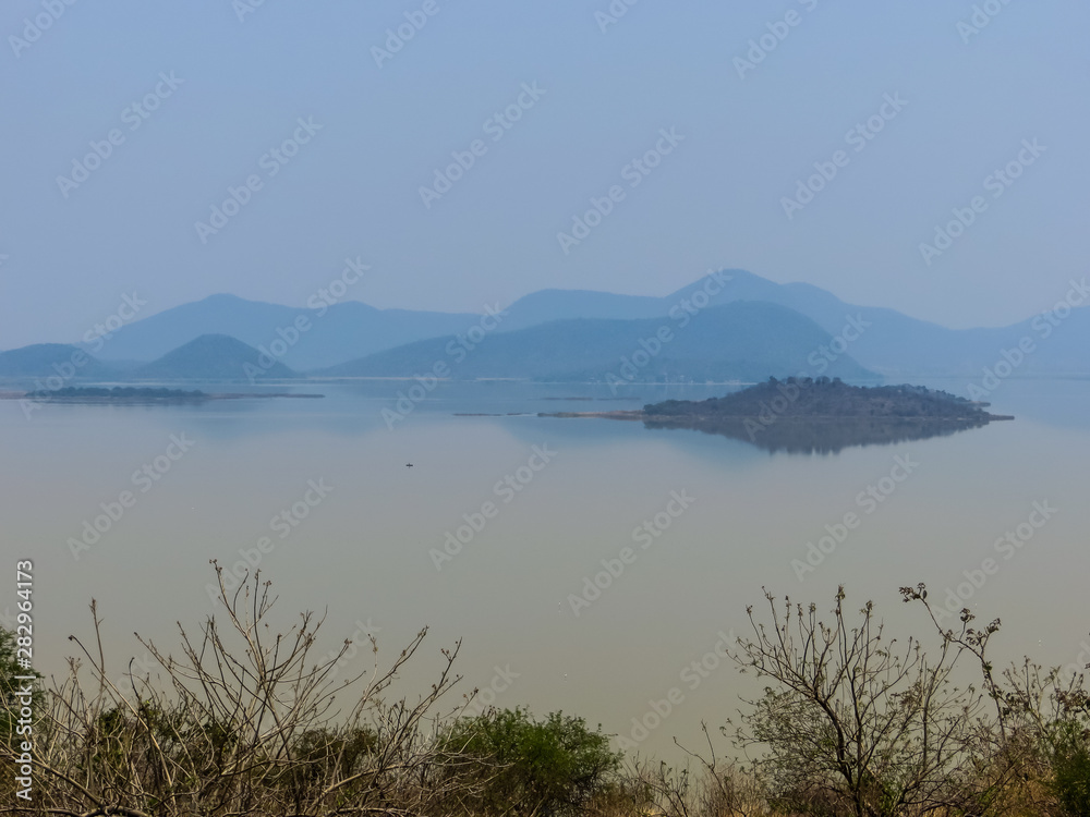 View of large lake with reflected hill and vegetation View of large lake with reflected hill and vegetation