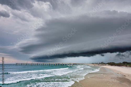 Fototapeta Naklejka Na Ścianę i Meble -  Large shelf cloud storm coming over sand pumping jetty during storm season australia