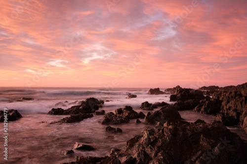 Red sky sunrise with water motion and flow over rocks