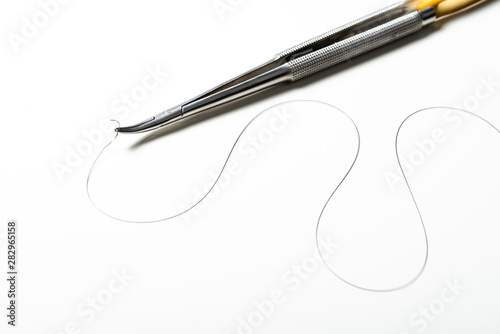 Suture needle holder with suture thread. Nylon surgical thread on white background and space for text.