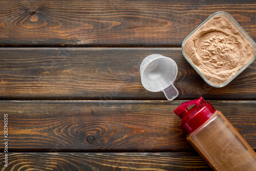 Nutrition for workout with protein cocktail powder and shaker on wooden background top view mockup