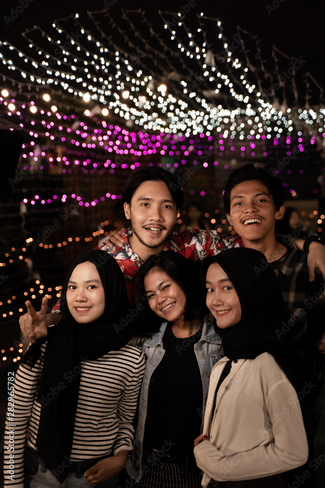 happy friends enjoy the night at outdoor rooftop cafe