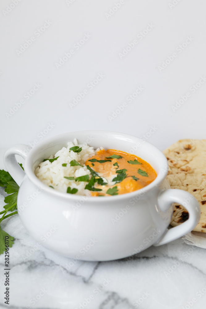 Indian butter chicken with rice, cilantro, and naan, copy space, white background