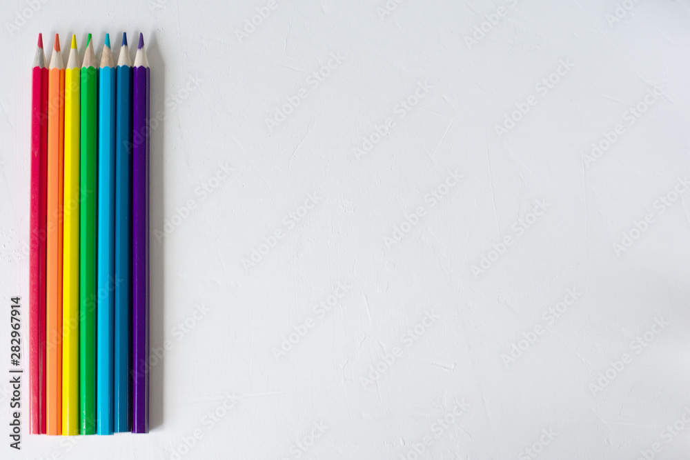 Many colored pencils lie on a white background. Copy spase. The concept of back to school, the educational process, study at school, drawing Many colored pencils lie on a white background. Copy spase. The concept of back to school, the educational process, study at school, drawing