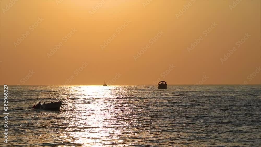 Boats passing the scenic natural landscape at sunset. Beautiful orange golden hour and boats swimming in the water. Boats passing the scenic natural landscape at sunset. Beautiful orange golden hour and boats swimming in the water.