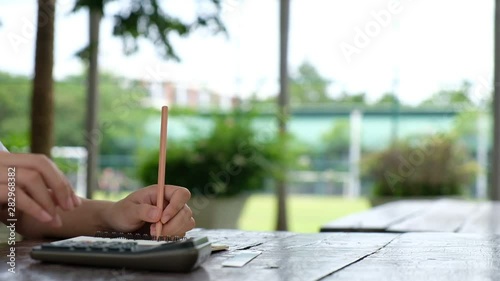 Cropped hand of woman doing homework on the desk, education outdoor concept, copy space use for presentation and background