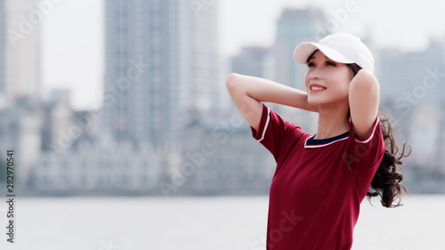 Fashion pretty young girl with black long hair, wearing red T-shirt and white baseball cap posing outdoor, minimalist urban clothing style.
