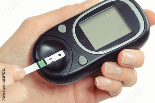 Hand of woman using glucose meter for measuring sugar level