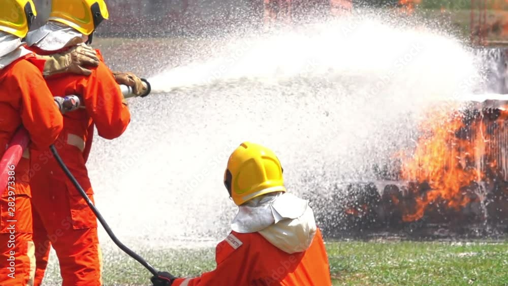 HD Slow motion wide shot firefighter in fire suit on safety rescue duty with crackle fire flames in burning oil truck. Firemen using chemical foam extinguisher fighting a fire inside burning premises