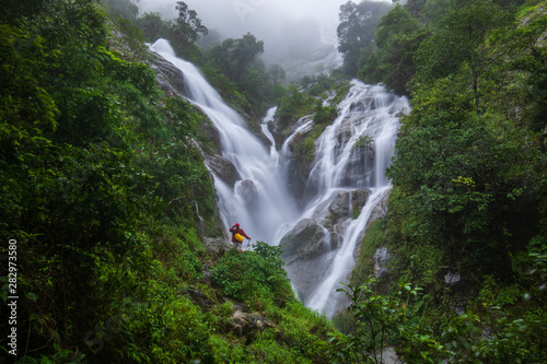 The girl in red sweater touring on Pi-tu-gro waterfall, Beautiful waterfall in Tak province, ThaiLand.