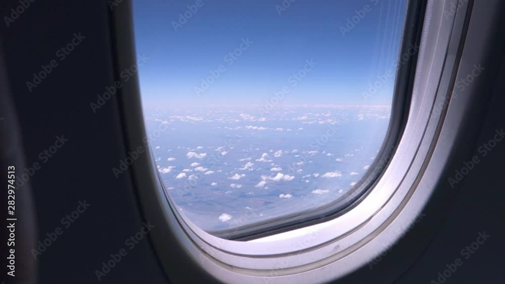 Airplane window with blue sky and white clouds. Business travel concept. Sunny day Airplane window with blue sky and white clouds. Business travel concept. Sunny day