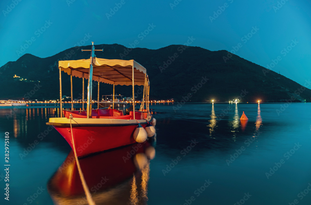 Long exposure teal and orange sunset view of Kotor Bay and a docked boat in postcard perfect town of Perast Montenegro