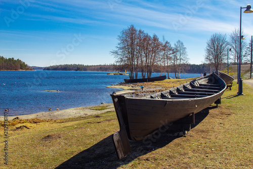 Finland. Savonlinna. Southern Savonia: Exhibit ancient boat on the lake at spring sunny day near the Lake Saimaa Nature and Museum Centre Riihisaari and Olavinlinna fortress - Olofsborg. photo