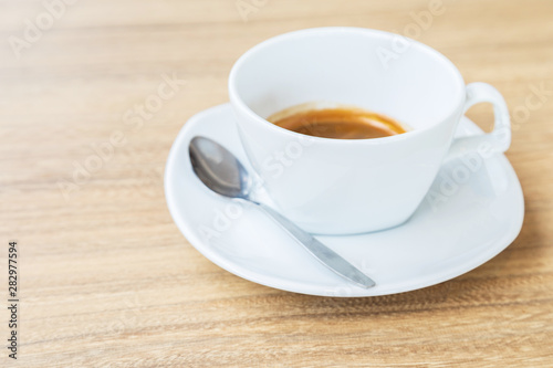 Black coffee in white cup on wooden background.