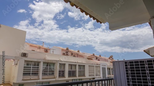 Clouds passing over apartment buildings seen from a balcony. Zooming in. photo