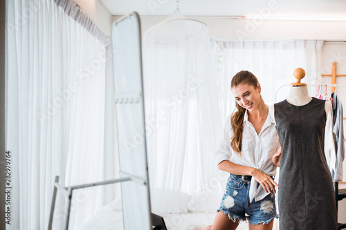 Young beautiful women standing in clothes shop and choosing dresses,Happy and smiling,Fashion and lifestyle concept photo