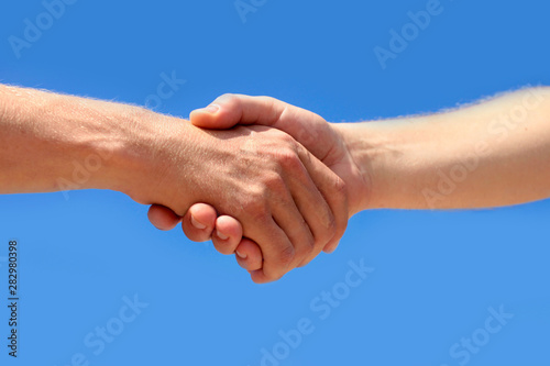 Business partnership meeting concept. Men is handshake against the background of clouds and the blue sky.Successful businessmen handshaking after good deal.