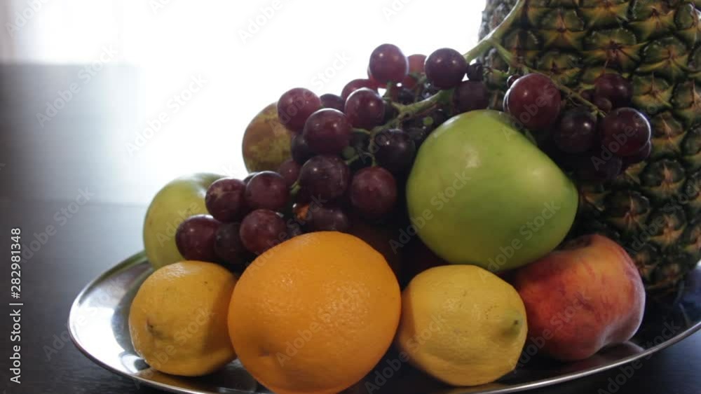 Fruit plate. Pineapple, apple, red grapes, lemon, orange. Camera moves around it. Fruit plate. Pineapple, apple, red grapes, lemon, orange. Camera moves around it.
