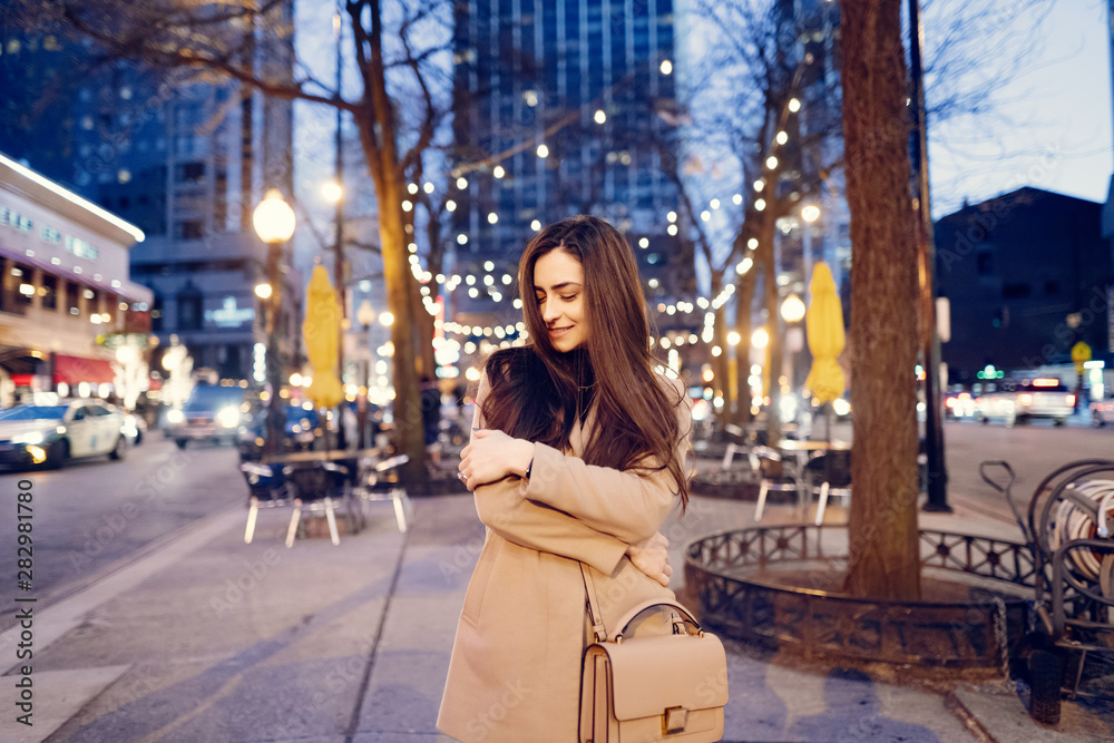 Beautiful girl in a evening city. Stylish brunette in a brown coat. Woman in a Chicago. Lady with a phone