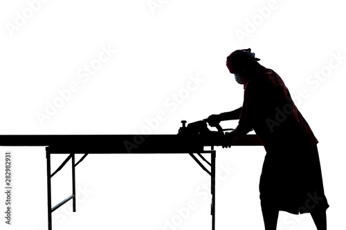 Isolated silhouette portrait of carpenter scrubs the wood with electrical tool at the construction site on white background photo