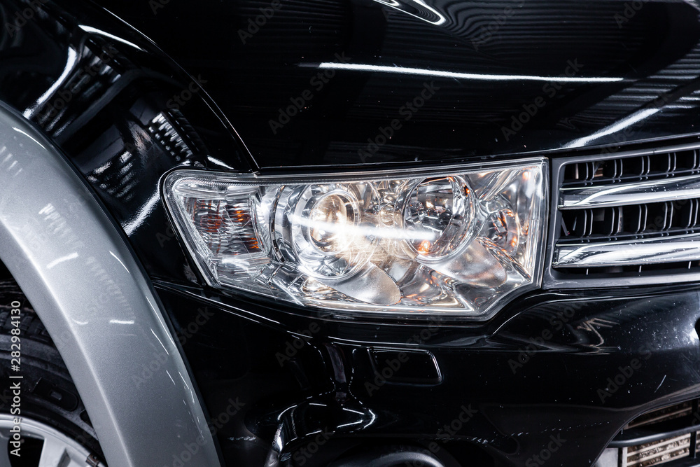 Close-up of the black headlight, bumper, wheel. Halogen headlight on a new car