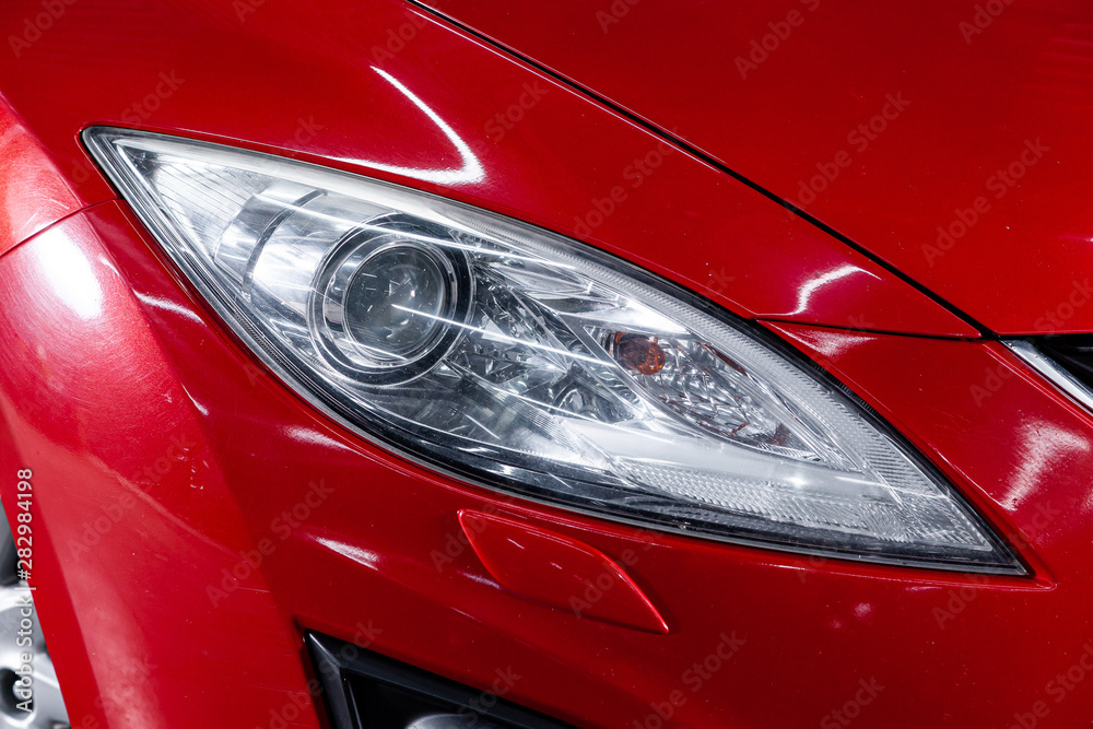 Close-up of the red headlight, bumper, wheel. Halogen headlight on a new car