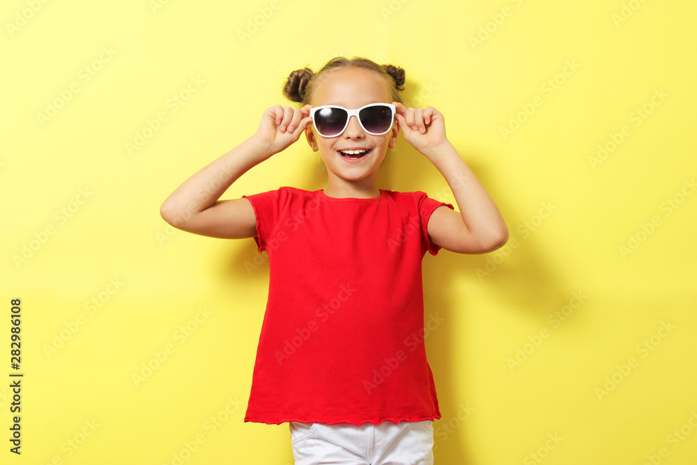 Little cheerful smiling girl in fashionable clothes on a colored background. Children's clothing, children's fashion Little cheerful smiling girl in fashionable clothes on a colored background. Children's clothing, children's fashion