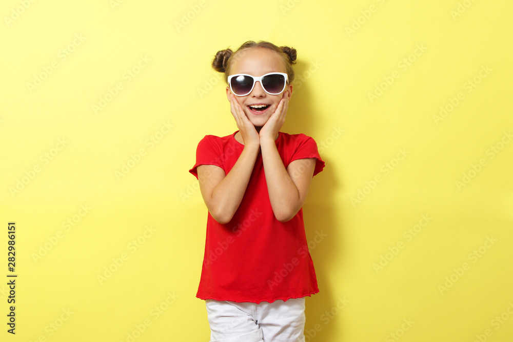 Little cheerful smiling girl in fashionable clothes on a colored background. Children's clothing, children's fashion Little cheerful smiling girl in fashionable clothes on a colored background. Children's clothing, children's fashion
