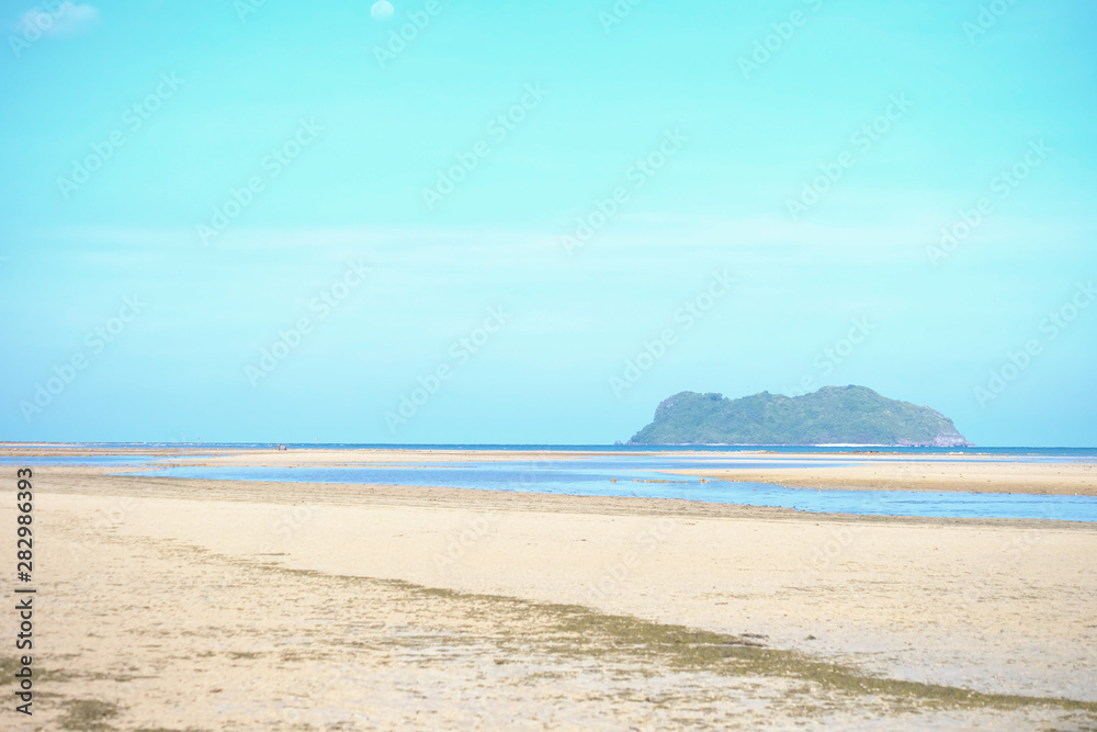 A beautiful sea beach with water run out and blurred a mountain,blue sky in bright day