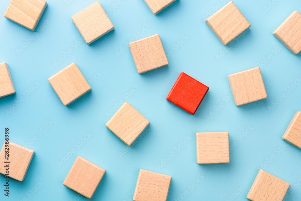 Red wooden block standing out from the group wooden blocks on blue background. Leadership, dissenting opinion, divergent views concepts Red wooden block standing out from the group wooden blocks on blue background. Leadership, dissenting opinion, divergent views concepts