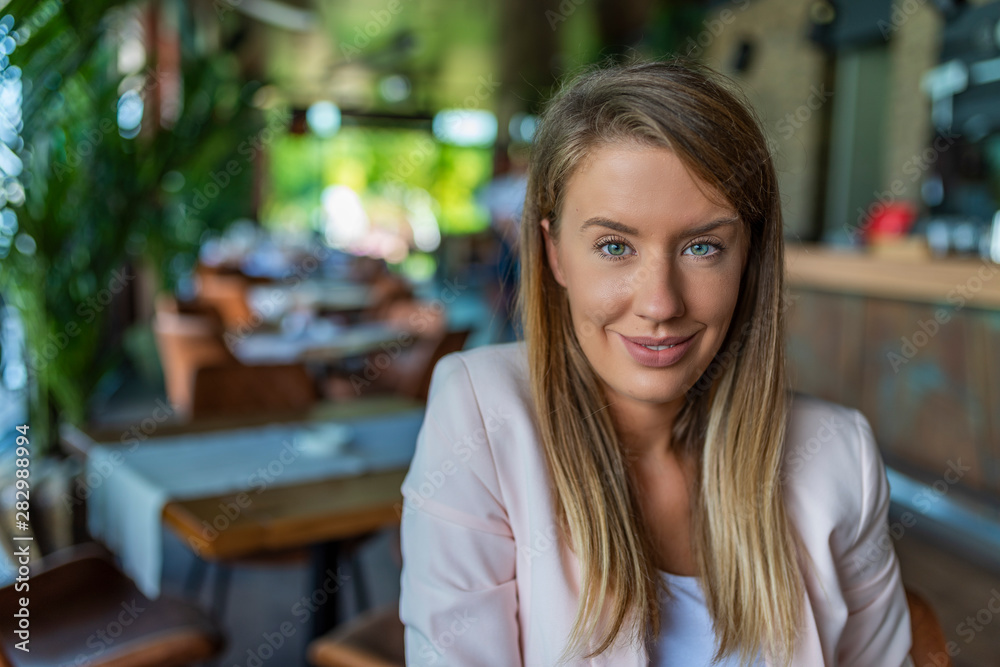 Closeup face of smiling woman sitting in cafeteria. Successful lady in a cafe pub. Portrait of woman smiling in coffee shop. Young smiling business woman sitting in cafe Closeup face of smiling woman sitting in cafeteria. Successful lady in a cafe pub. Portrait of woman smiling in coffee shop. Young smiling business woman sitting in cafe