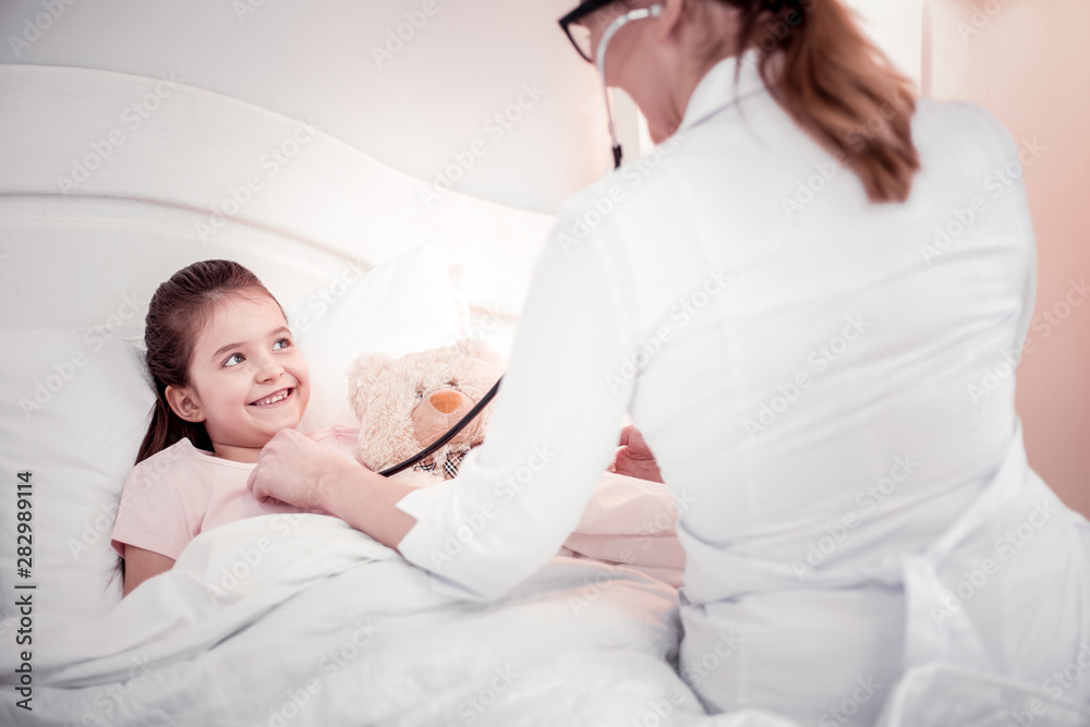 Positive nice cute girl smiling to her doctor Positive nice cute girl smiling to her doctor