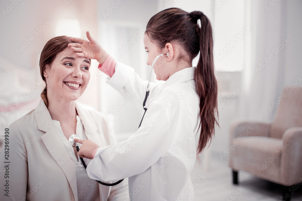 Fototapeta premium Positive smart girl touching her moms forehead