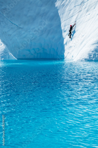 Female ice climber over deep blue water of the Matanuska Glacier photo